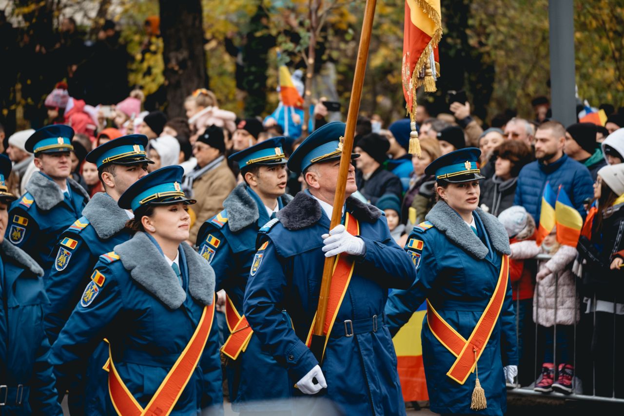 Mastering the First Impression: Your intriguing post title goes here A military parade in Bucharest featuring uniformed soldiers marching with flags amidst a gathered crowd.
